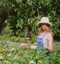 a woman in overalls standing in a flower garden